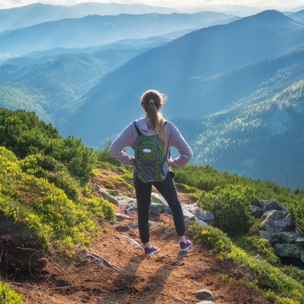 mountains-and-standing-young-woman-with-backpack-on-the-trail